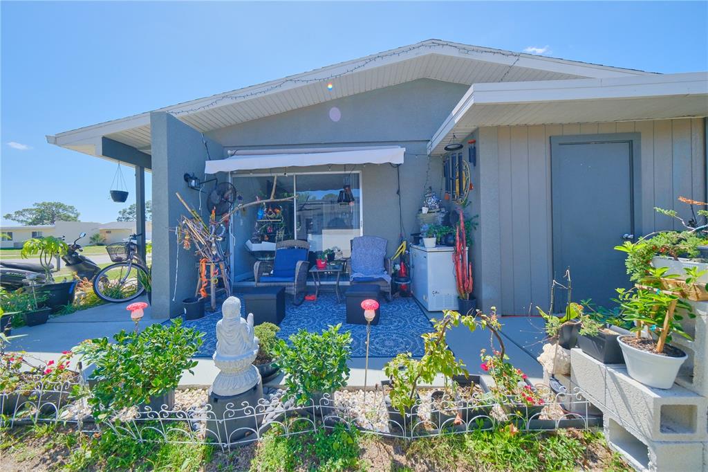 A patio area features a blue rug, outdoor furniture, potted plants, and a sliding glass door — 6231 CONISTON TERRACE, NORTH PORT, FL