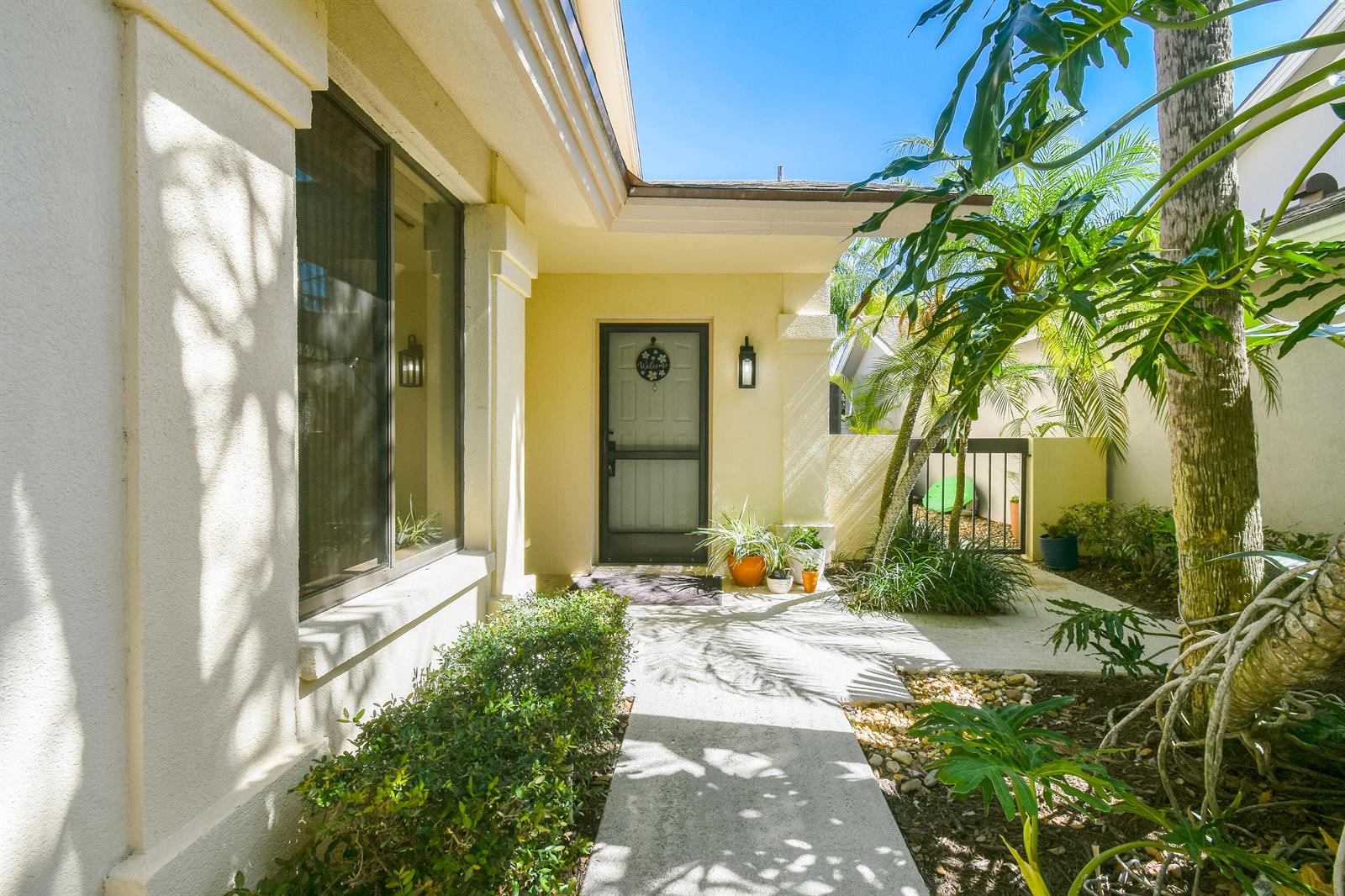 A concrete walkway leads to the front entrance of a house with a screen door — 137 Harbourside Circle, Jupiter FL 33477, JUPITER, FL
