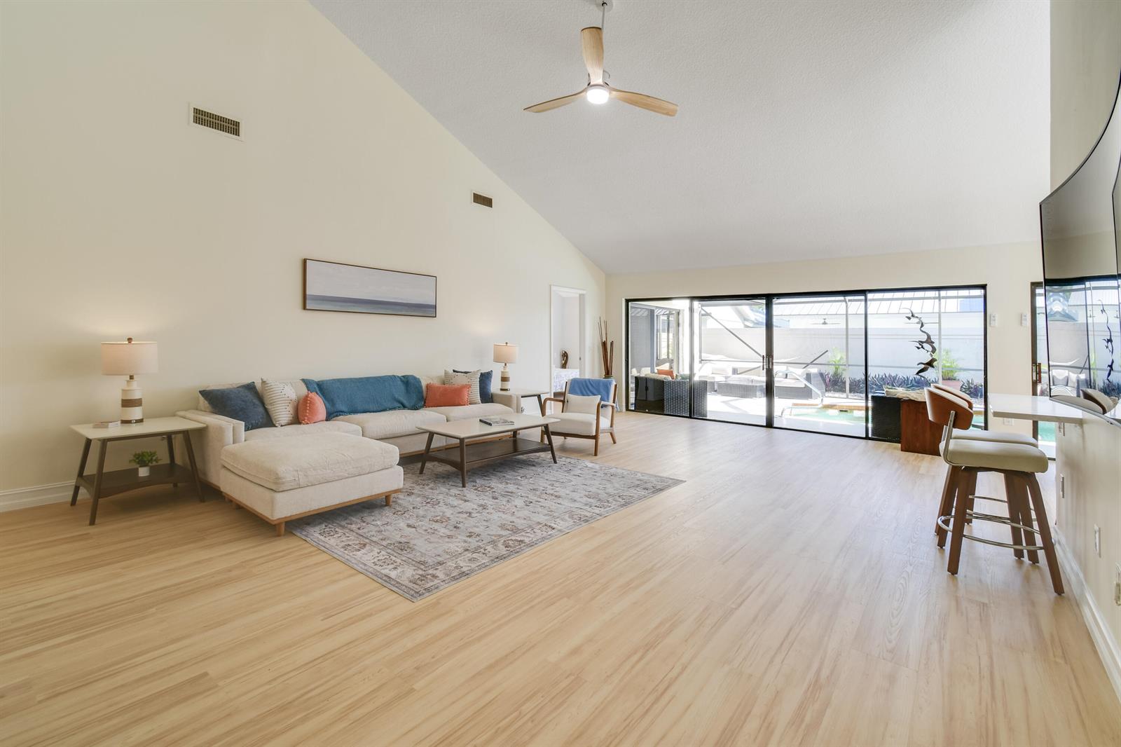 A spacious living room features vaulted ceilings, light wood flooring, and large sliding glass doors — 137 Harbourside Circle, Jupiter FL 33477, JUPITER, FL