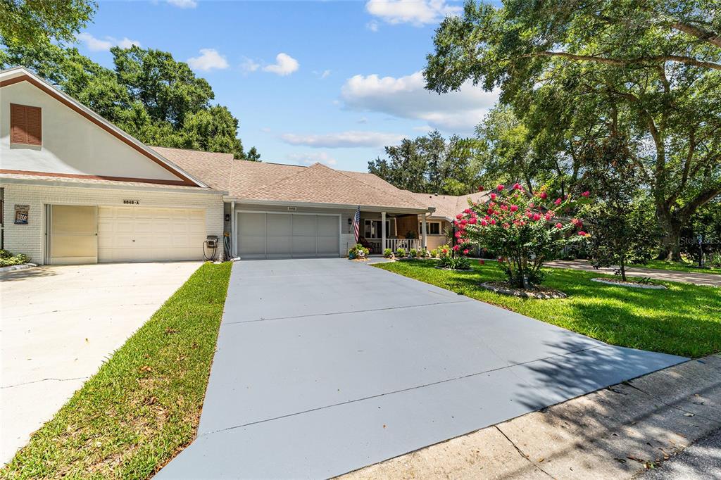 A single-story house with a two-car garage, a gray driveway, and a blooming crape myrtle — 8649 SW 92ND PLACE UNIT B, OCALA, FL