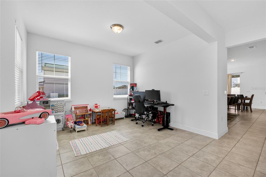 A room with tile flooring, two windows, a gaming desk, and children's toys — 2263 RAVEN RIDGE, CLERMONT, FL