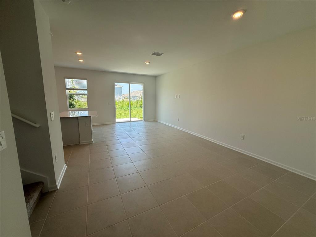 An open-concept living area features light-colored tile flooring, a kitchen island, and sliding glass doors — 2567 SKYLINE LOOP, KISSIMMEE, FL