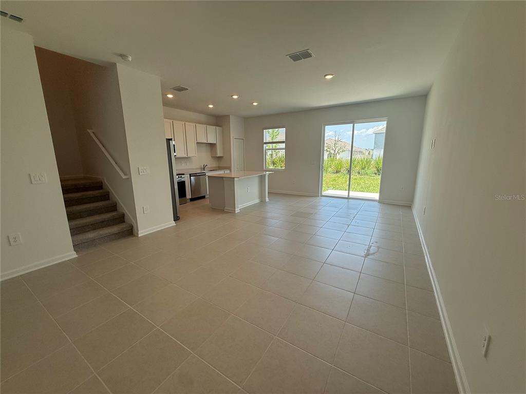 An open-concept kitchen and living area features tile flooring, white cabinetry, and a sliding door — 2567 SKYLINE LOOP, KISSIMMEE, FL