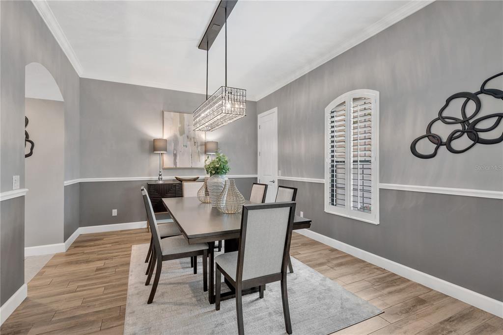 A dining room features a rectangular table, upholstered chairs, a crystal chandelier, and gray walls — 9127 TILLINGHAST DRIVE, TAMPA, FL