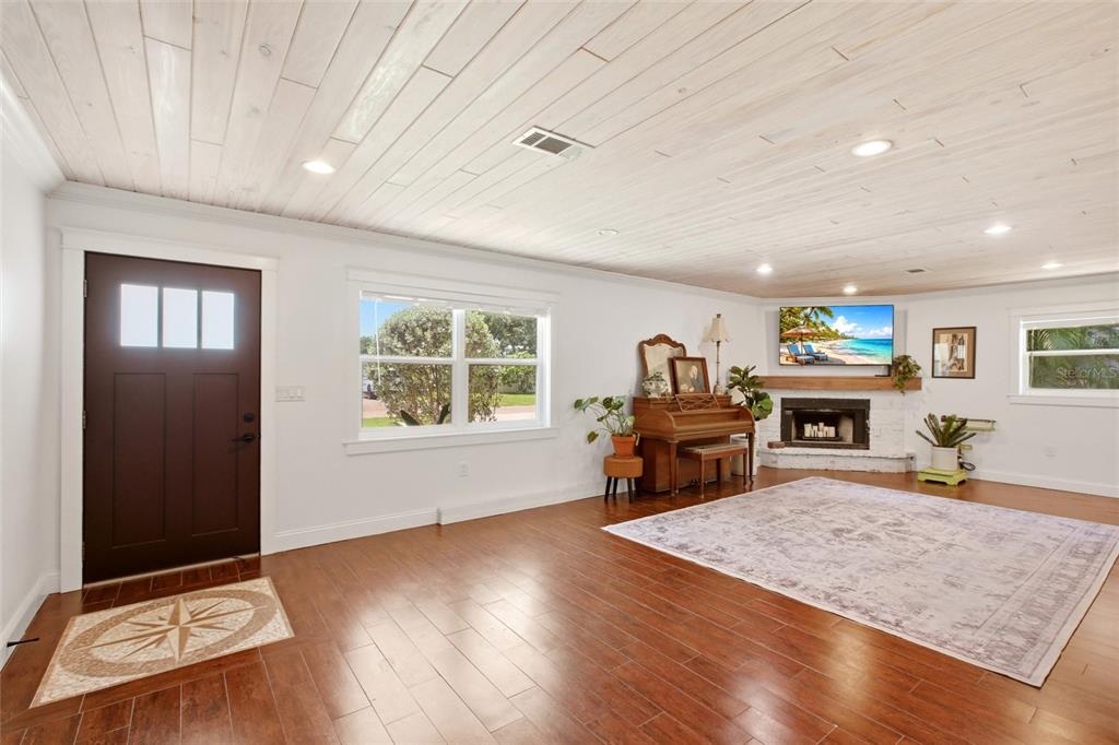 A living room features a wood-plank ceiling, dark hardwood floors, a fireplace, and a piano — 706 18TH AVENUE DRIVE W, PALMETTO, FL