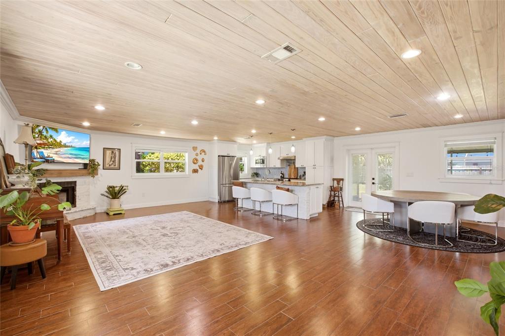 An open-concept living and dining area features a wood-paneled ceiling and dark wood flooring — 706 18TH AVENUE DRIVE W, PALMETTO, FL