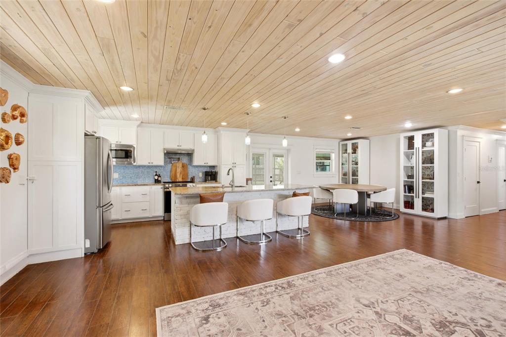 A kitchen and dining area features white cabinetry, a brick island, and a wood-paneled ceiling — 706 18TH AVENUE DRIVE W, PALMETTO, FL