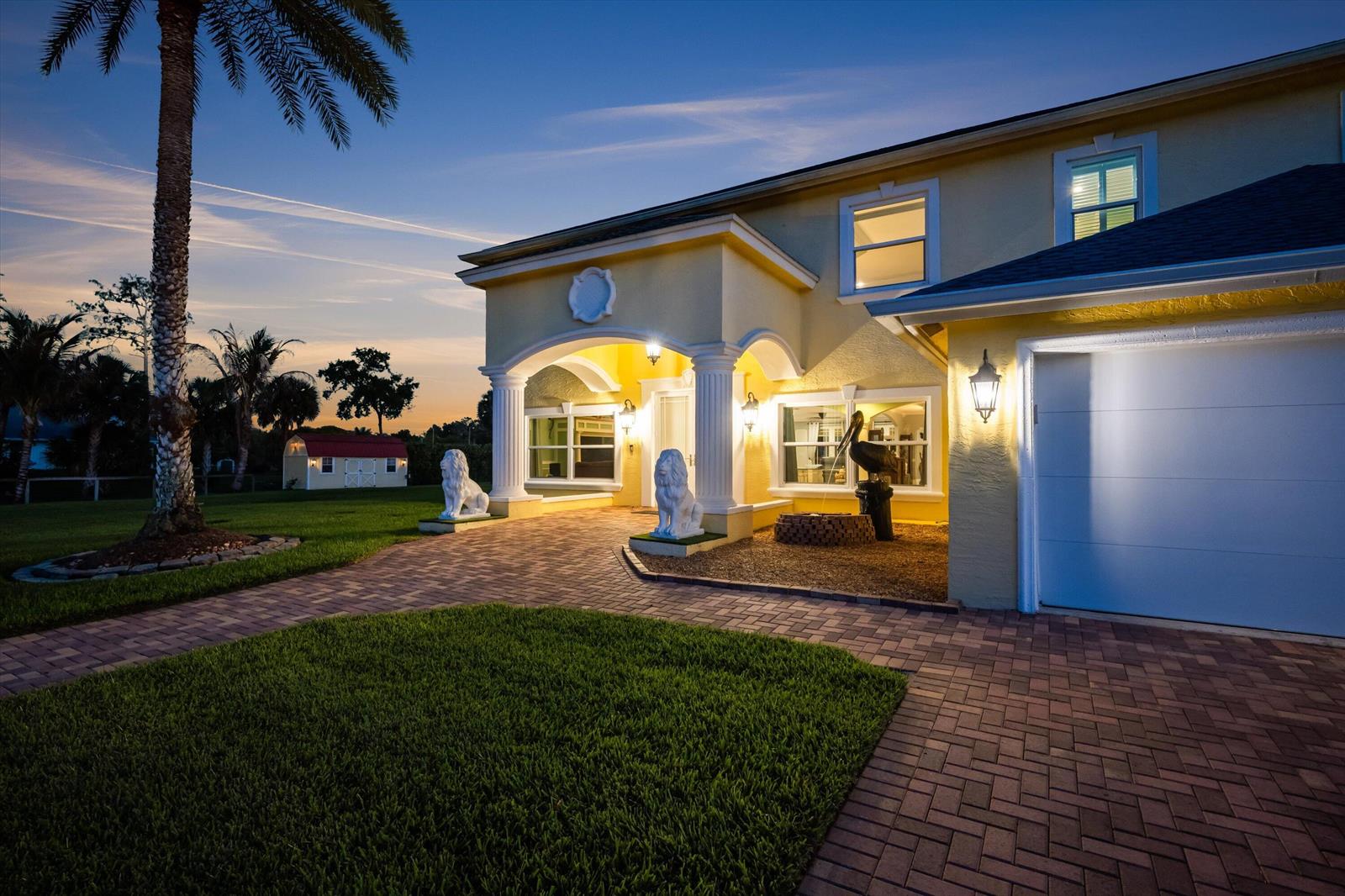 A yellow two-story house with a brick driveway, lion statues, and a palm tree — 17948 N 33rd Rd Road N, FL 33470, FL