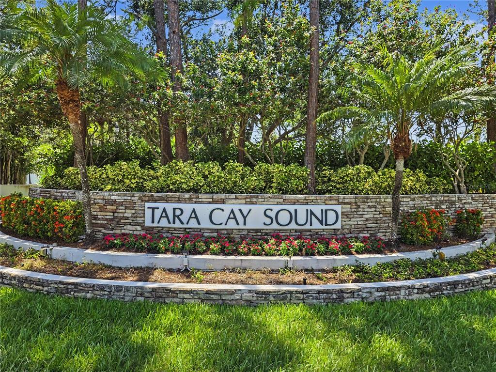 A stone monument sign for Tara Cay Sound sits in front of lush landscaping and trees — 9870 INDIAN KEY TRAIL UNIT 64, SEMINOLE, FL