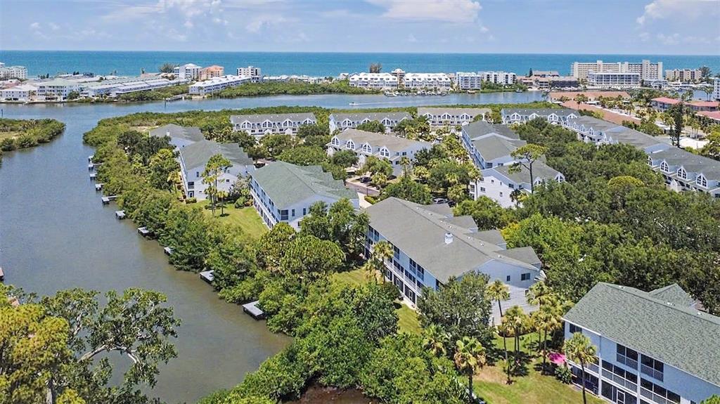 An aerial view shows multiple white multi-story residential buildings surrounded by trees and waterways — 9870 INDIAN KEY TRAIL UNIT 64, SEMINOLE, FL