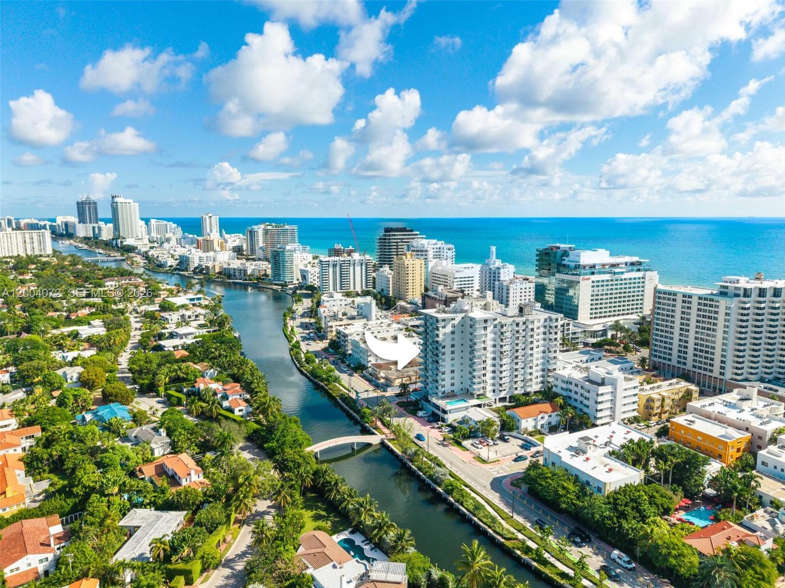 An aerial view shows a canal flowing between a residential neighborhood and high-rise buildings — 2829 Indian Creek Dr # 1002, Miami Beach FL 33140, MIAMI BEACH, FL