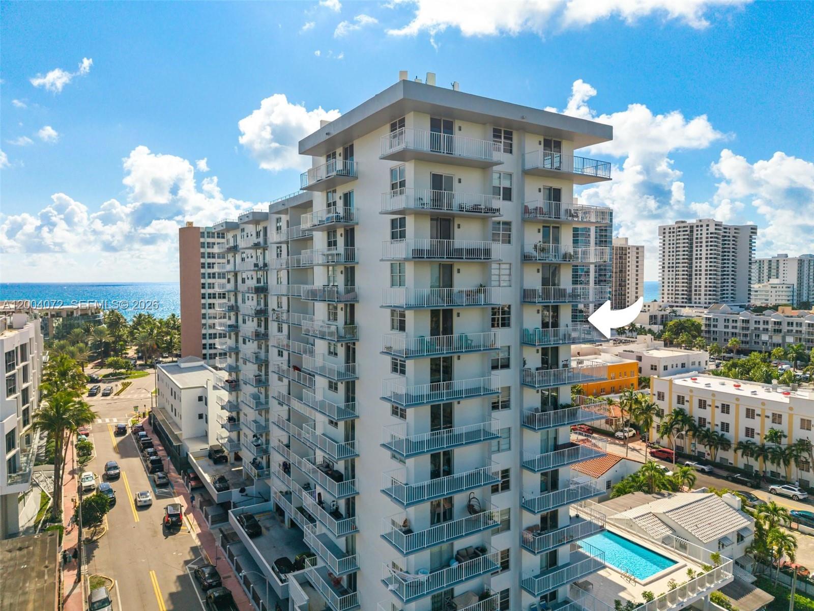 An aerial view of a high-rise residential building with balconies overlooking a swimming pool — 2829 Indian Creek Dr # 1002, Miami Beach FL 33140, MIAMI BEACH, FL