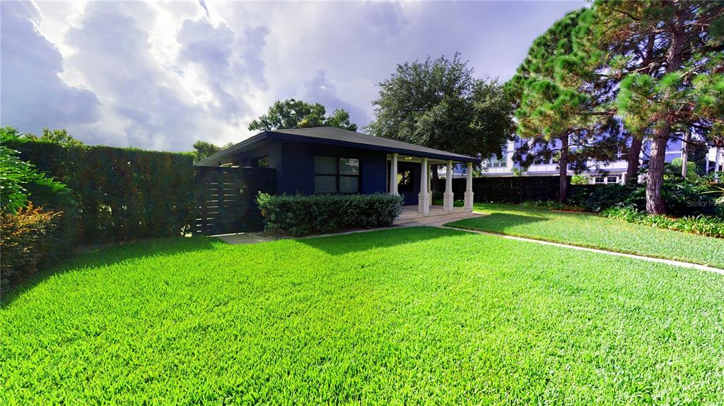 A dark blue house with a covered porch sits behind a large, manicured green lawn — 218 S MATANZAS AVENUE, TAMPA, FL