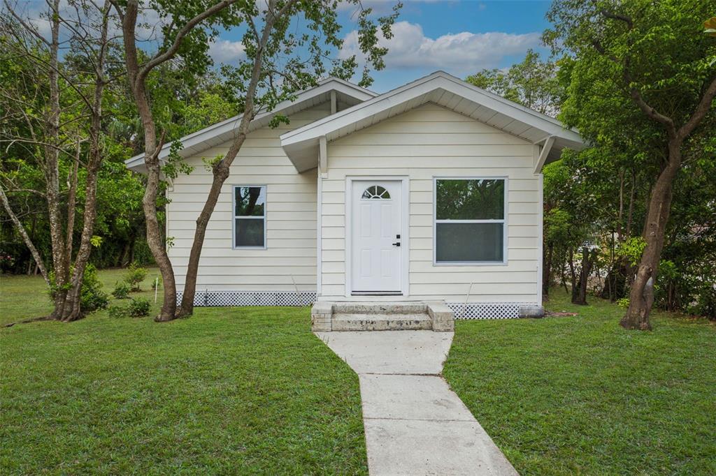 A small, light-colored, single-story house with a white front door and a concrete walkway — 4660 7TH AVENUE N, ST PETERSBURG, FL