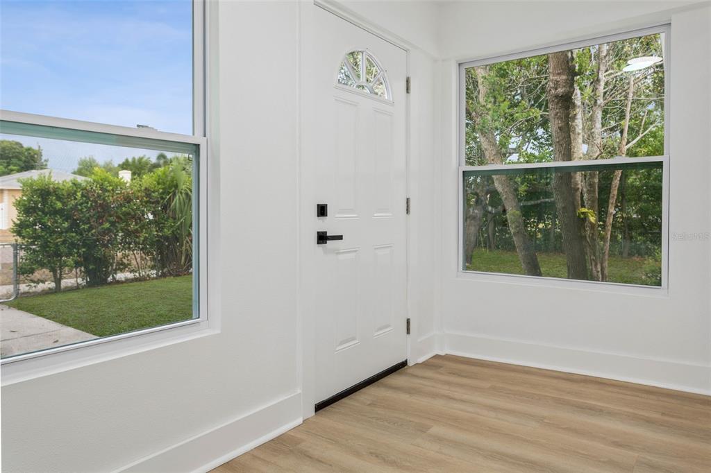 A bright room with white walls, light wood flooring, a front door, and two windows — 4660 7TH AVENUE N, ST PETERSBURG, FL
