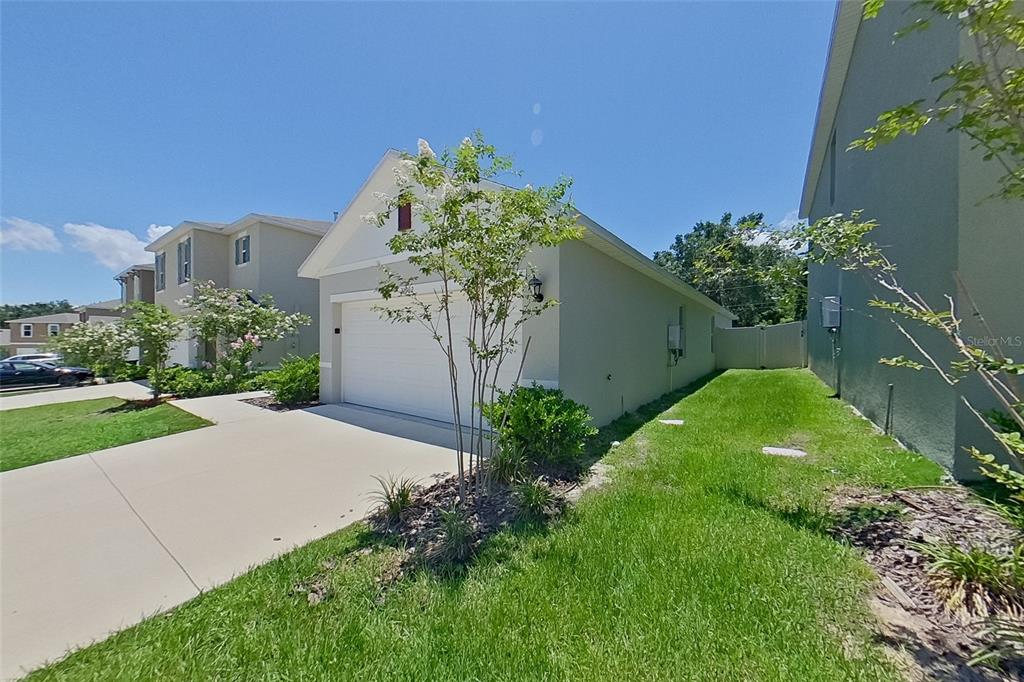A side view of a suburban house exterior featuring a garage and a grassy yard — 31962 KATELIN CIRCLE, LEESBURG, FL