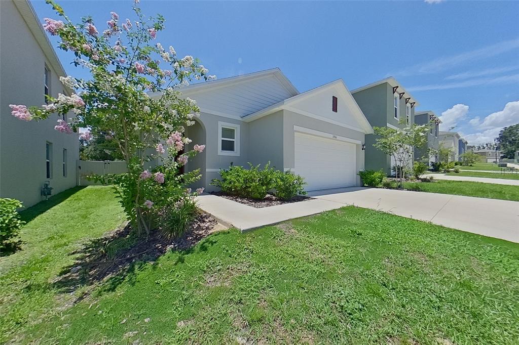 A light gray single-story house with a two-car garage and a blooming crape myrtle tree — 31962 KATELIN CIRCLE, LEESBURG, FL