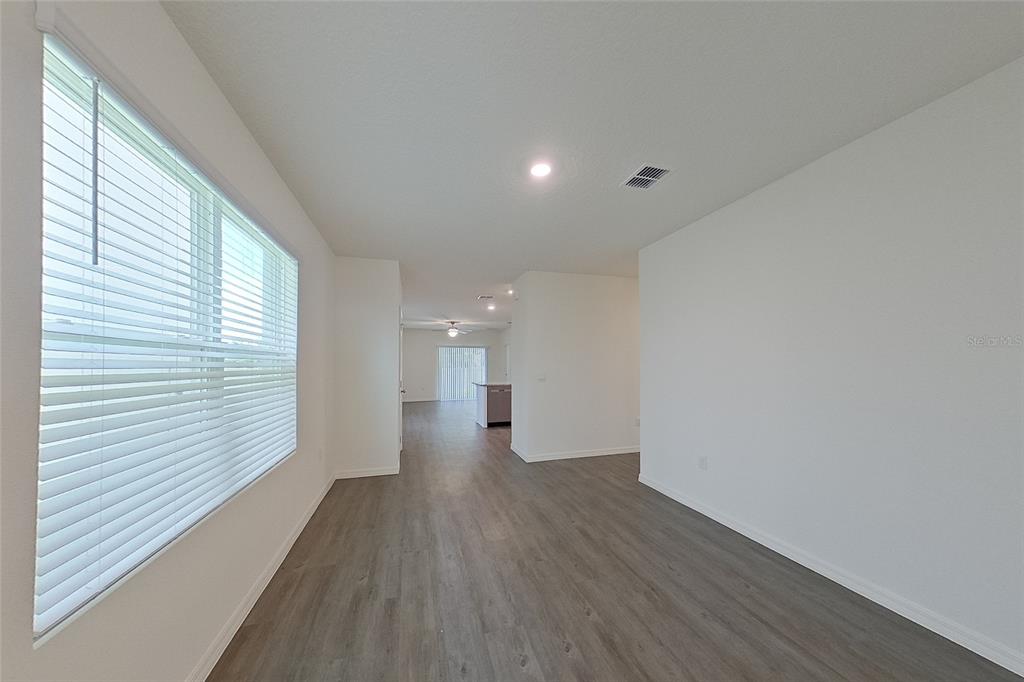 An empty room with white walls, gray wood-look flooring, and a large window with blinds — 31962 KATELIN CIRCLE, LEESBURG, FL