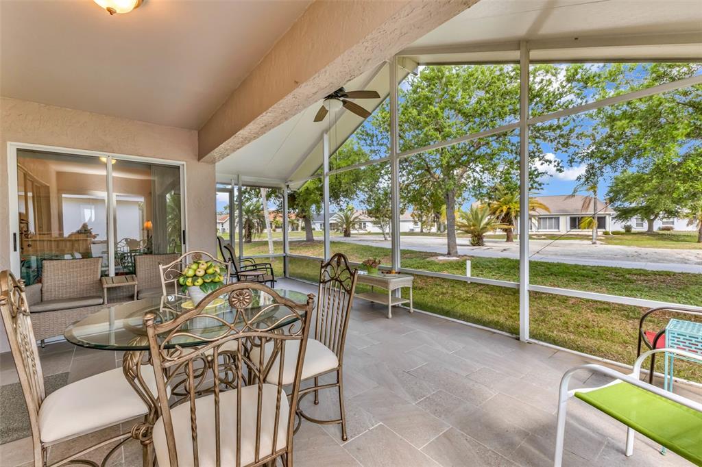 A screened-in patio with tile flooring, a glass dining table, and views of a neighborhood — 1869 BIRMINGHAM BOULEVARD, PUNTA GORDA, FL