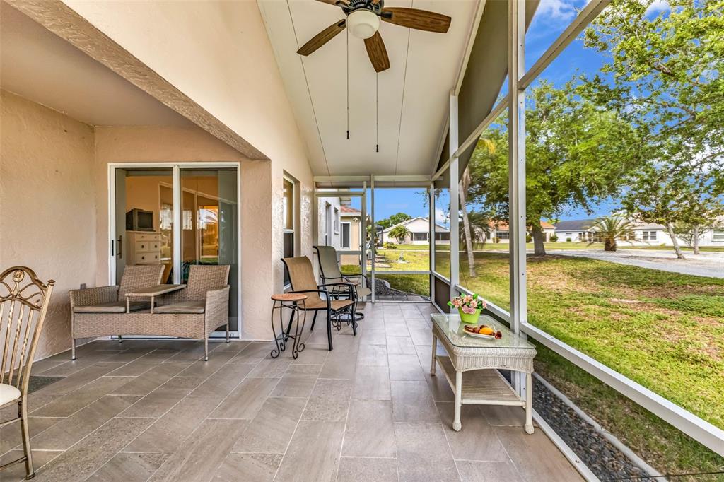 A screened-in patio features tile flooring, outdoor furniture, and a ceiling fan — 1869 BIRMINGHAM BOULEVARD, PUNTA GORDA, FL