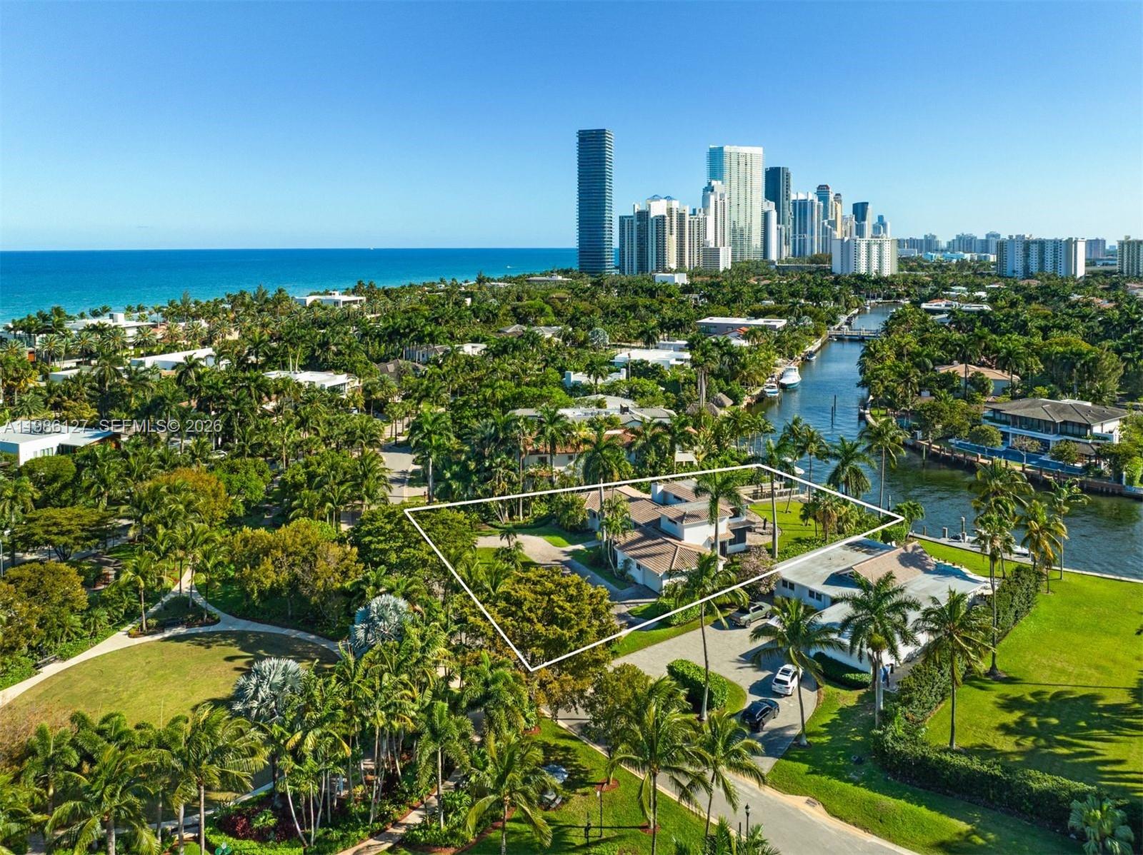 An aerial view shows a house with a large yard near a canal and city — 268 S Parkway, Golden Beach FL 33160, GOLDEN BEACH, FL