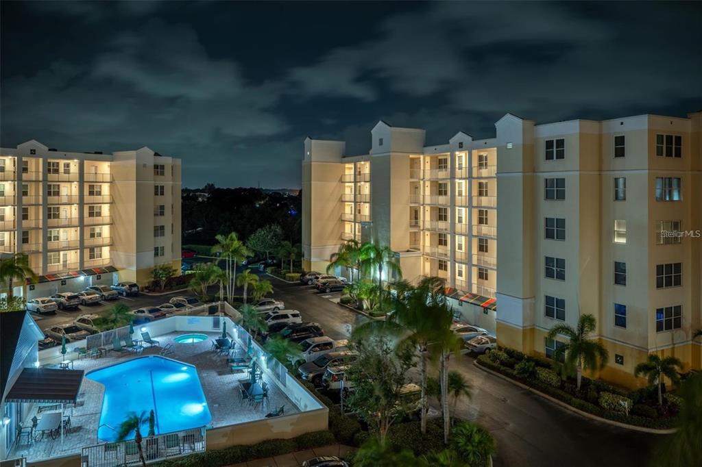 An exterior night view of apartment buildings featuring a swimming pool and parking lot — 1200 COUNTRY CLUB DRIVE UNIT 2205, LARGO, FL