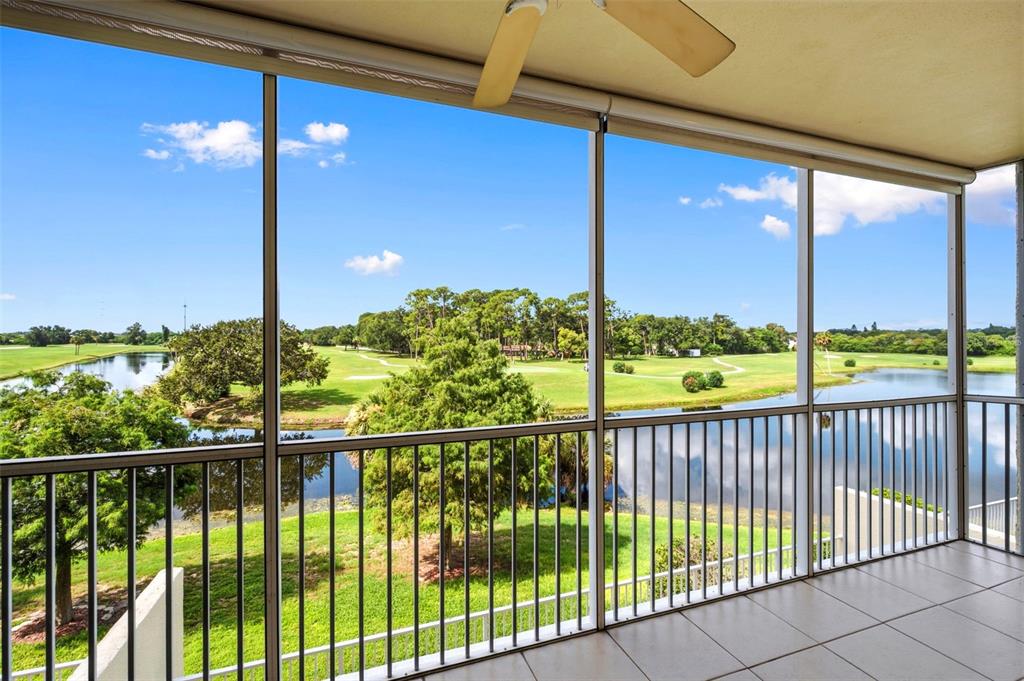 A screened-in balcony with tile flooring overlooks a golf course and a pond — 1200 COUNTRY CLUB DRIVE UNIT 2205, LARGO, FL