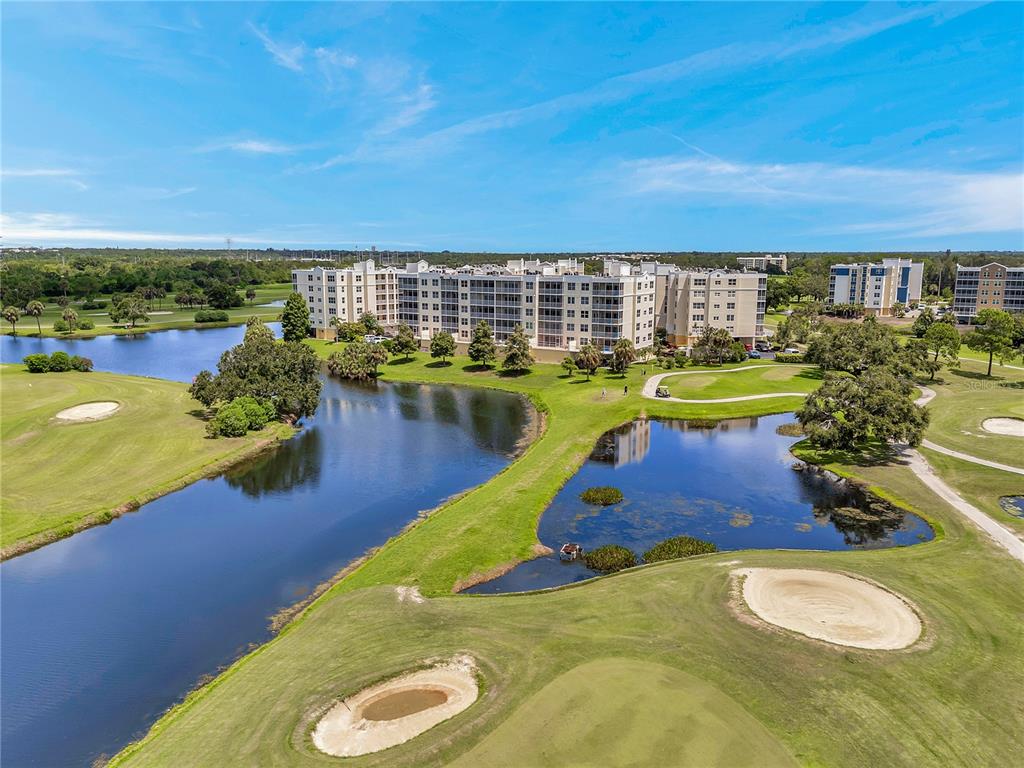 An aerial view of a multi-story apartment building situated on a golf course with ponds — 1200 COUNTRY CLUB DRIVE UNIT 2205, LARGO, FL