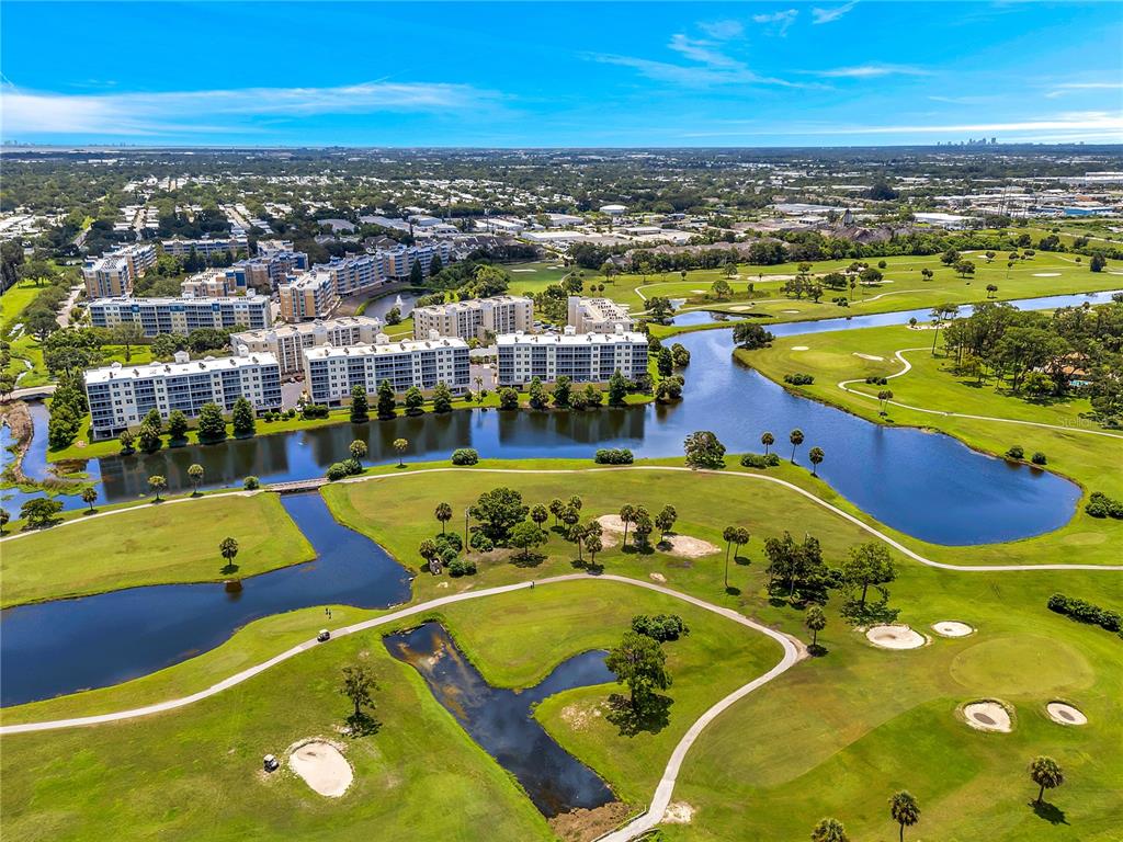 An aerial view shows multi-story apartment buildings situated along a lake and a golf course — 1200 COUNTRY CLUB DRIVE UNIT 2205, LARGO, FL
