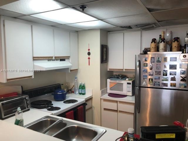 A kitchen features white cabinets, a stainless steel refrigerator, and a double-basin sink — 540 Brickell Key Dr # 1116, Miami FL 33131, MIAMI, FL