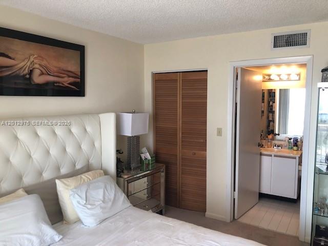 A bedroom features a tufted white headboard, a bedside table, and an adjacent bathroom door — 540 Brickell Key Dr # 1116, Miami FL 33131, MIAMI, FL