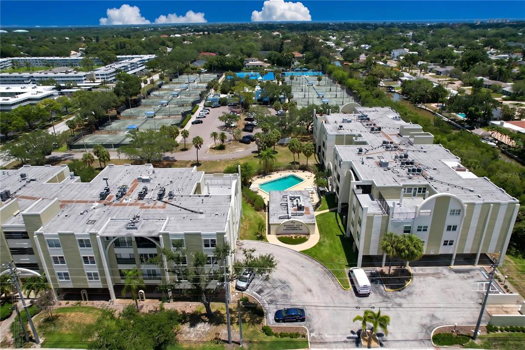An aerial view shows two multi-story apartment buildings, a swimming pool, and several tennis courts — 4651 1ST STREET NE UNIT 311, ST PETERSBURG, FL