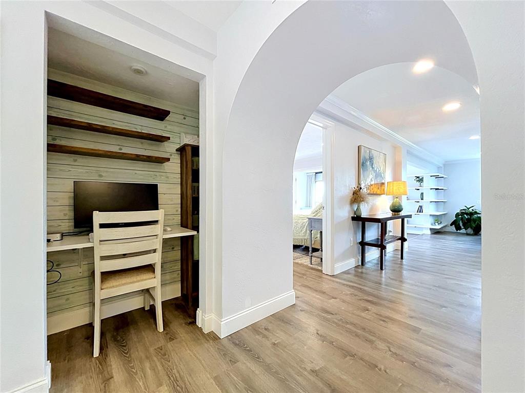A home office nook with wood-plank walls sits beside an arched entryway leading to living areas — 4651 1ST STREET NE UNIT 311, ST PETERSBURG, FL