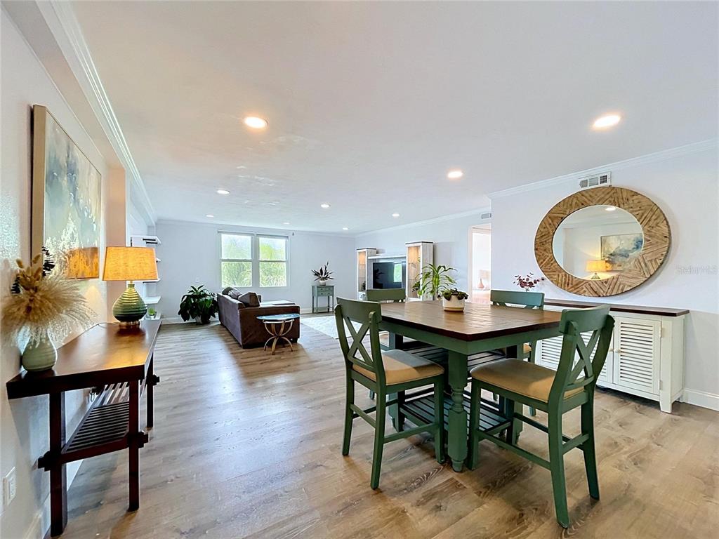 A dining area with green chairs and a living room with wood-look flooring — 4651 1ST STREET NE UNIT 311, ST PETERSBURG, FL