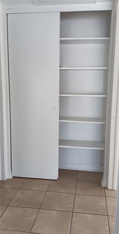 A white sliding door closet with multiple interior shelves stands above a tiled floor — 885 BELTREES STREET UNIT 12, DUNEDIN, FL