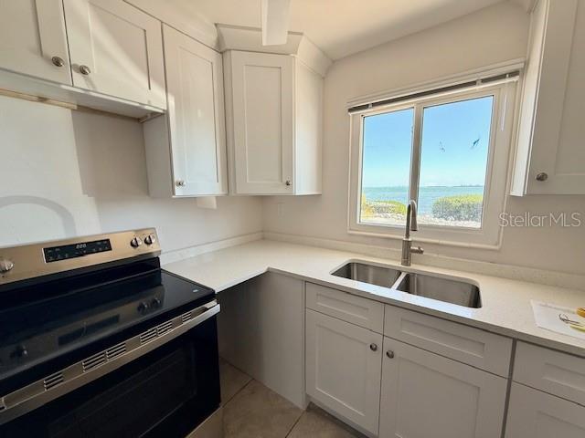 A kitchen features white cabinets, a stainless steel stove, and a window overlooking the water — 747 SAINT JUDES DRIVE S UNIT 2, LONGBOAT KEY, FL