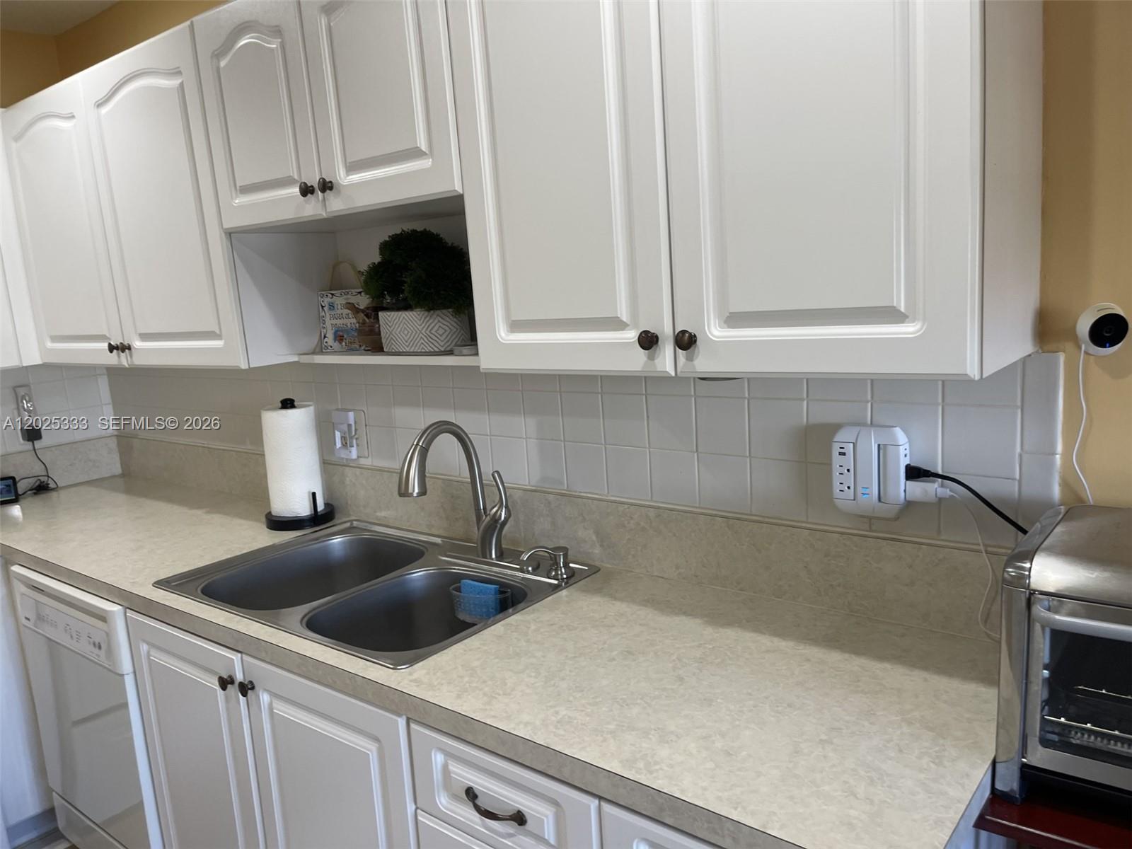 A kitchen features white cabinets, a double-basin stainless steel sink, and a laminate countertop — 1640 NW 19th Ter # 103, Delray Beach FL 33445, DELRAY BEACH, FL