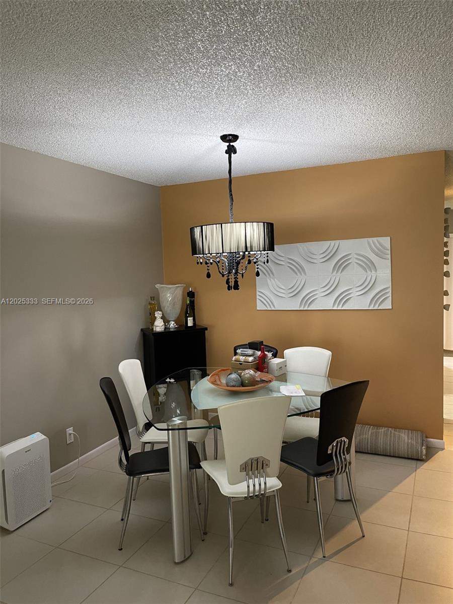 A dining room features a glass-topped table, modern chairs, and a black drum chandelier — 1640 NW 19th Ter # 103, Delray Beach FL 33445, DELRAY BEACH, FL