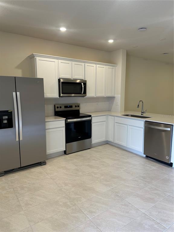 A kitchen features white cabinets, stainless steel appliances, and light-colored tile flooring — 2511 BRIGHT JEWEL STREET, KISSIMMEE, FL