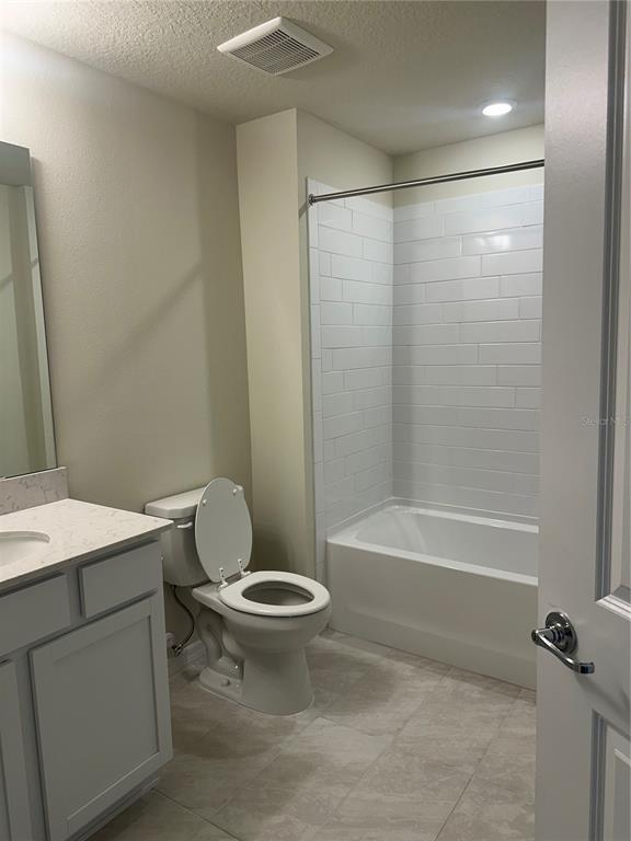 A bathroom features a white vanity, a toilet, and a tub with white subway tile — 2511 BRIGHT JEWEL STREET, KISSIMMEE, FL