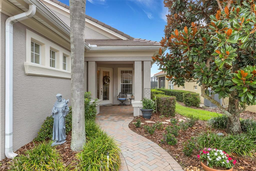 A paved walkway leads to the covered front entrance of a house with a statue — 2530 LAUREL GLEN DRIVE, LAKELAND, FL