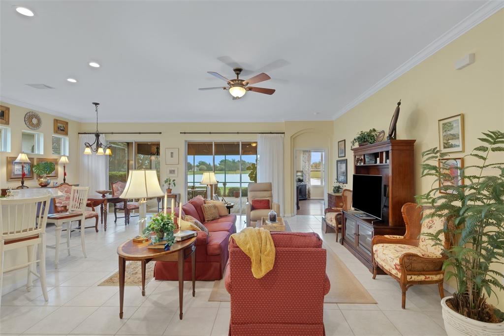 A living room with tile floors, a red sofa, a television, and sliding glass doors — 2530 LAUREL GLEN DRIVE, LAKELAND, FL