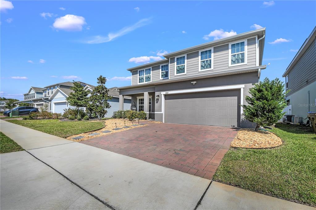 A two-story house with gray siding, a brick paver driveway, and a two-car garage — 3005 SLOUGH CREEK DRIVE, KISSIMMEE, FL