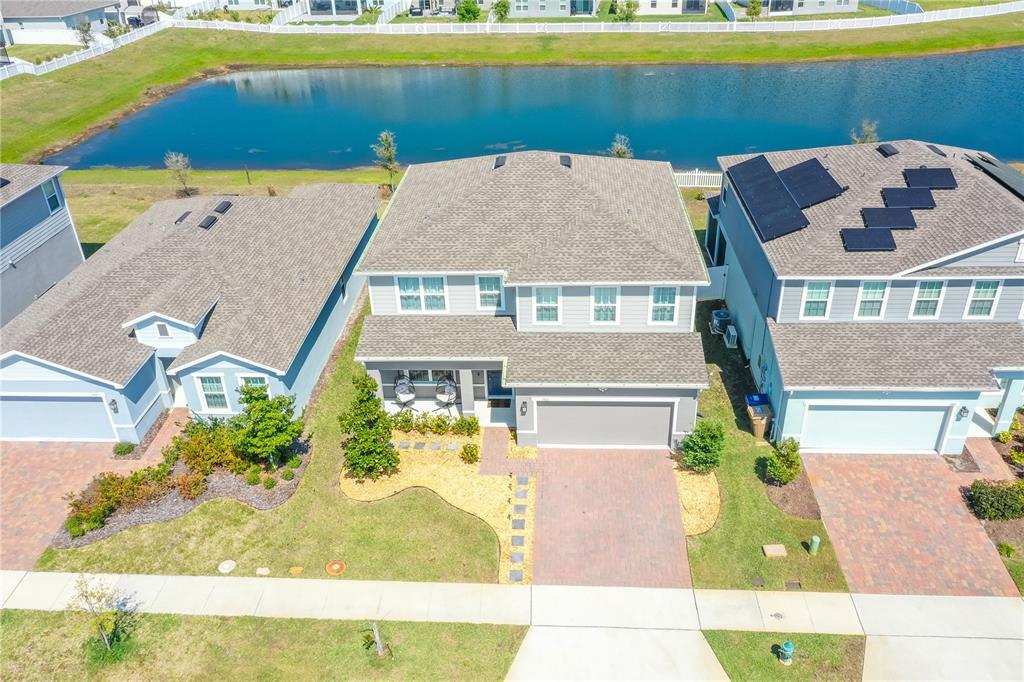 An aerial view shows a two-story suburban house with a paved driveway and backyard pond — 3005 SLOUGH CREEK DRIVE, KISSIMMEE, FL