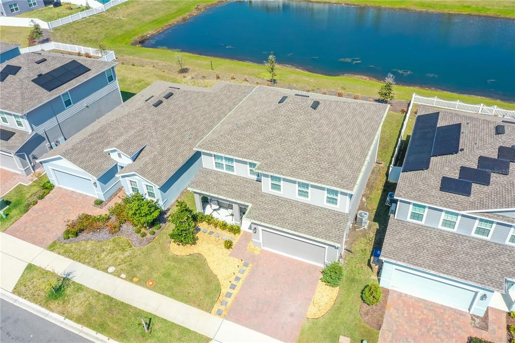 An aerial view shows a two-story suburban house with a paved driveway and backyard pond — 3005 SLOUGH CREEK DRIVE, KISSIMMEE, FL