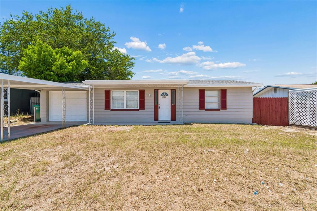 A single-story house with light siding, red shutters, and an attached carport — 3521 OAKHURST DRIVE, HOLIDAY, FL