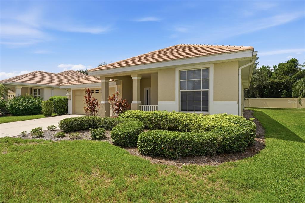 A single-story house with a tan stucco exterior, a tiled roof, and a manicured front lawn — 2771 WHISPERING PINE LANE, NORTH PORT, FL