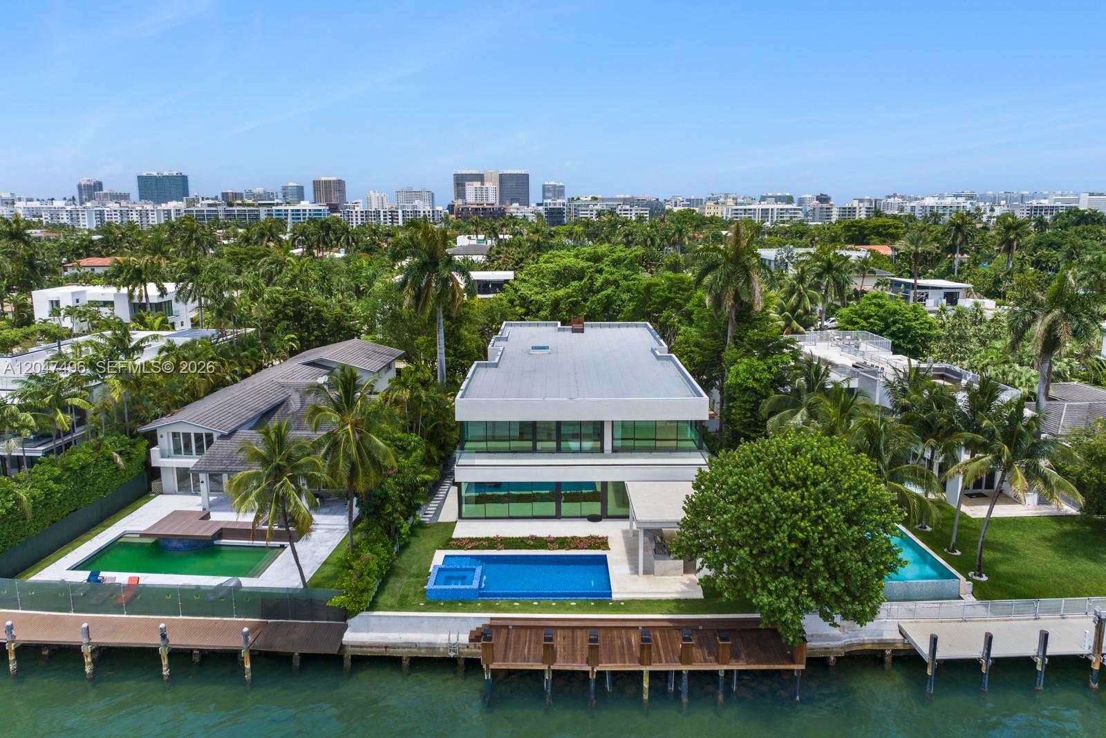 An aerial view shows a modern three-story house with a swimming pool and private dock — 9720 W Broadview Dr, Bay Harbor Islands FL 33154, BAY HARBOR ISLANDS, FL