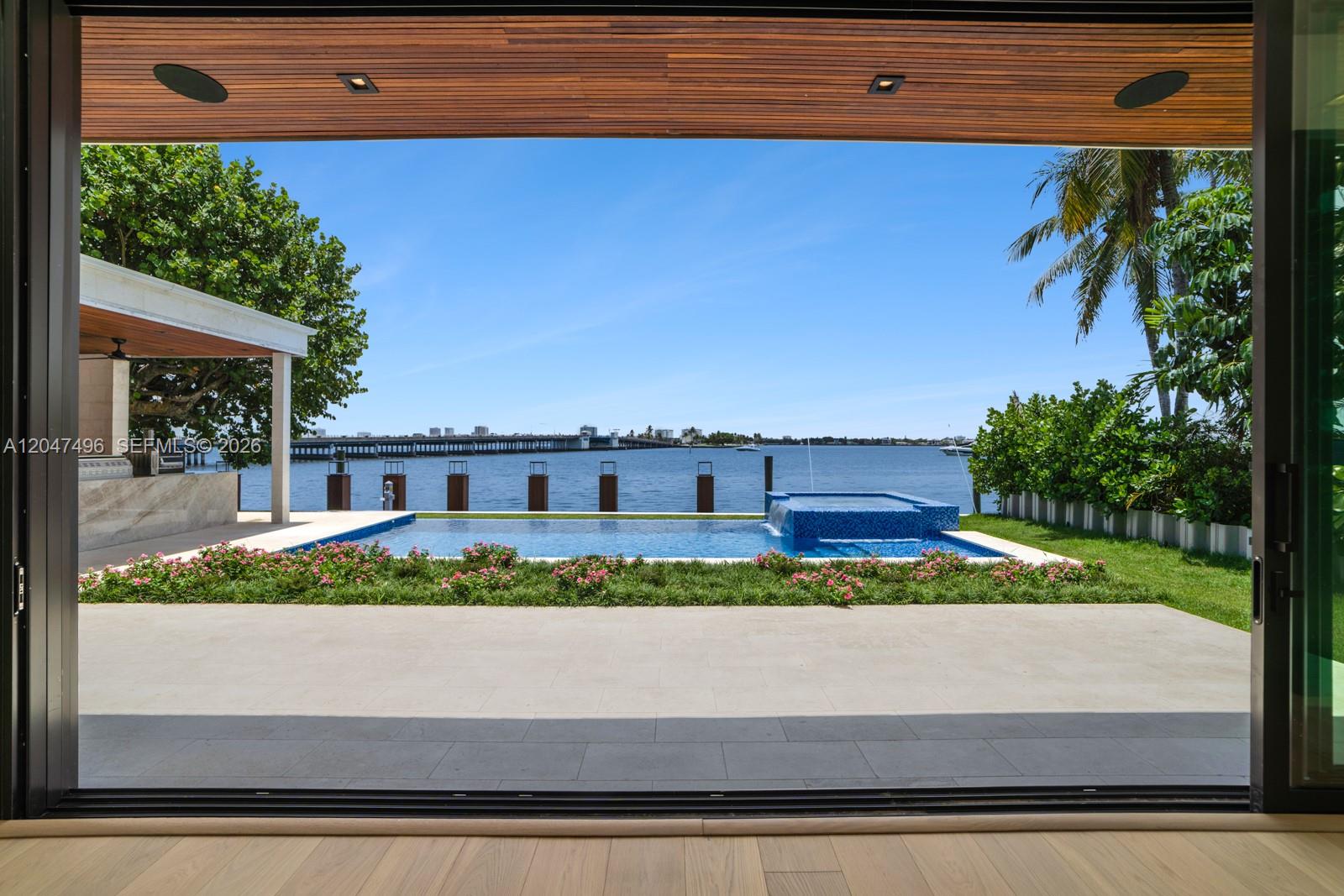 A view from an indoor space looking out at a swimming pool and waterfront — 9720 W Broadview Dr, Bay Harbor Islands FL 33154, BAY HARBOR ISLANDS, FL
