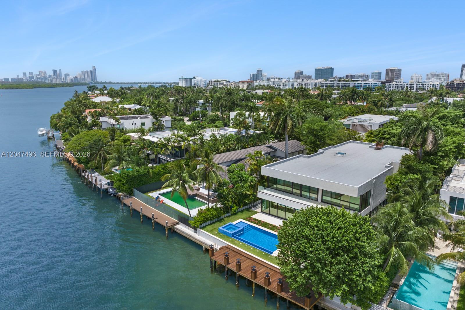 An aerial view shows waterfront luxury homes with swimming pools, docks, and lush tropical landscaping — 9720 W Broadview Dr, Bay Harbor Islands FL 33154, BAY HARBOR ISLANDS, FL